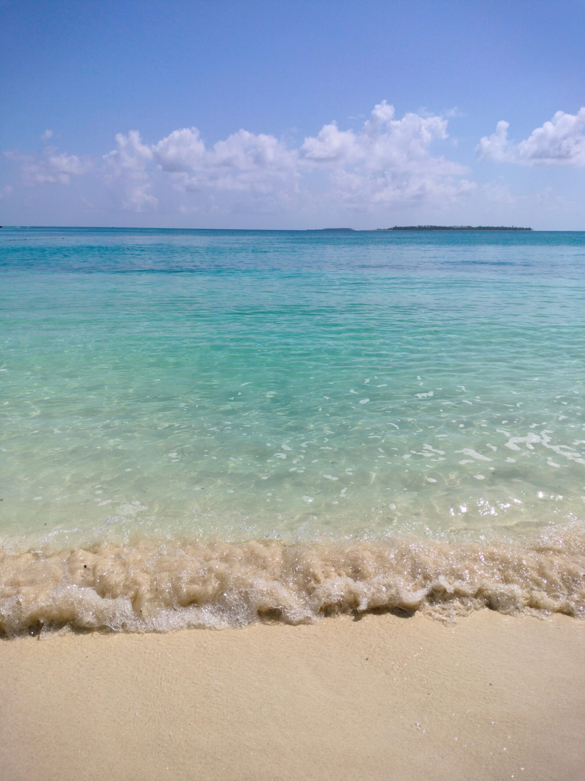 Mer turquoise calme et plage de sable sous un ciel clair
